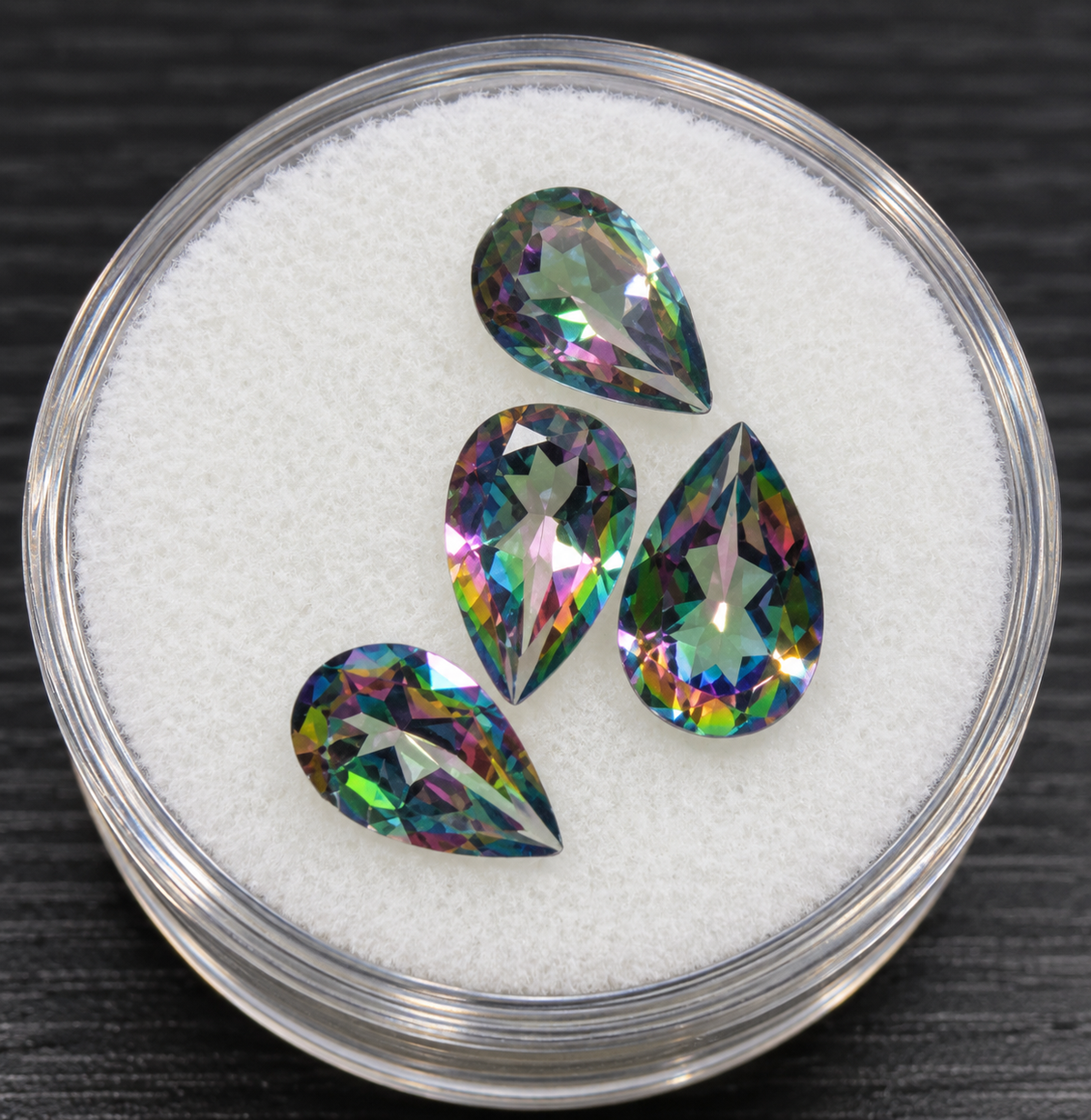 Stylized cropped promotional photo of four pear cut mystic topaz stones, without fingers