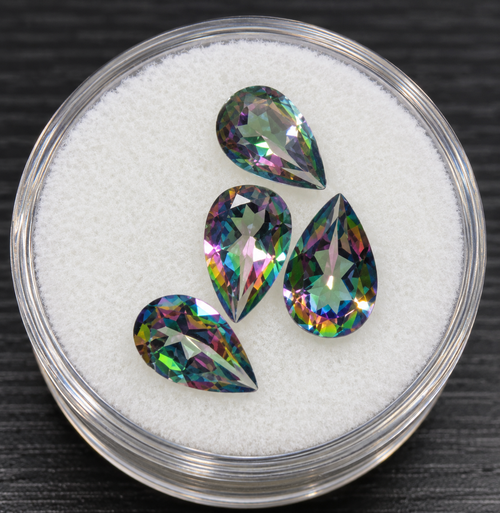 Stylized cropped promotional photo of four pear cut mystic topaz stones, without fingers